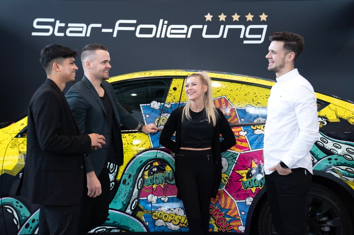 Vier Mitglieder des StarFolierung Teams vor einem farbenfroh folierten Fahrzeug in Kaarst